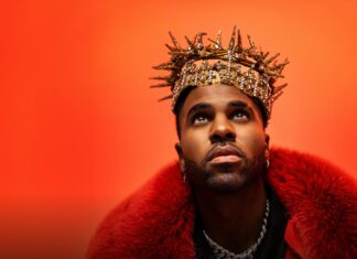 Jason Derulo olha para cima com expressão intensa, vestindo um casaco de pele vermelho e uma coroa dourada decorada com cristais, sobre fundo laranja vibrante. - Ingressos para Jason Derulo em Bolonha 2026