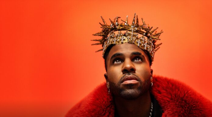 Jason Derulo em Bolonha ao vivo: onde comprar ingressos Jason Derulo olha para cima com expressão intensa, vestindo um casaco de pele vermelho e uma coroa dourada decorada com cristais, sobre fundo laranja vibrante. - Ingressos para Jason Derulo em Bolonha 2026