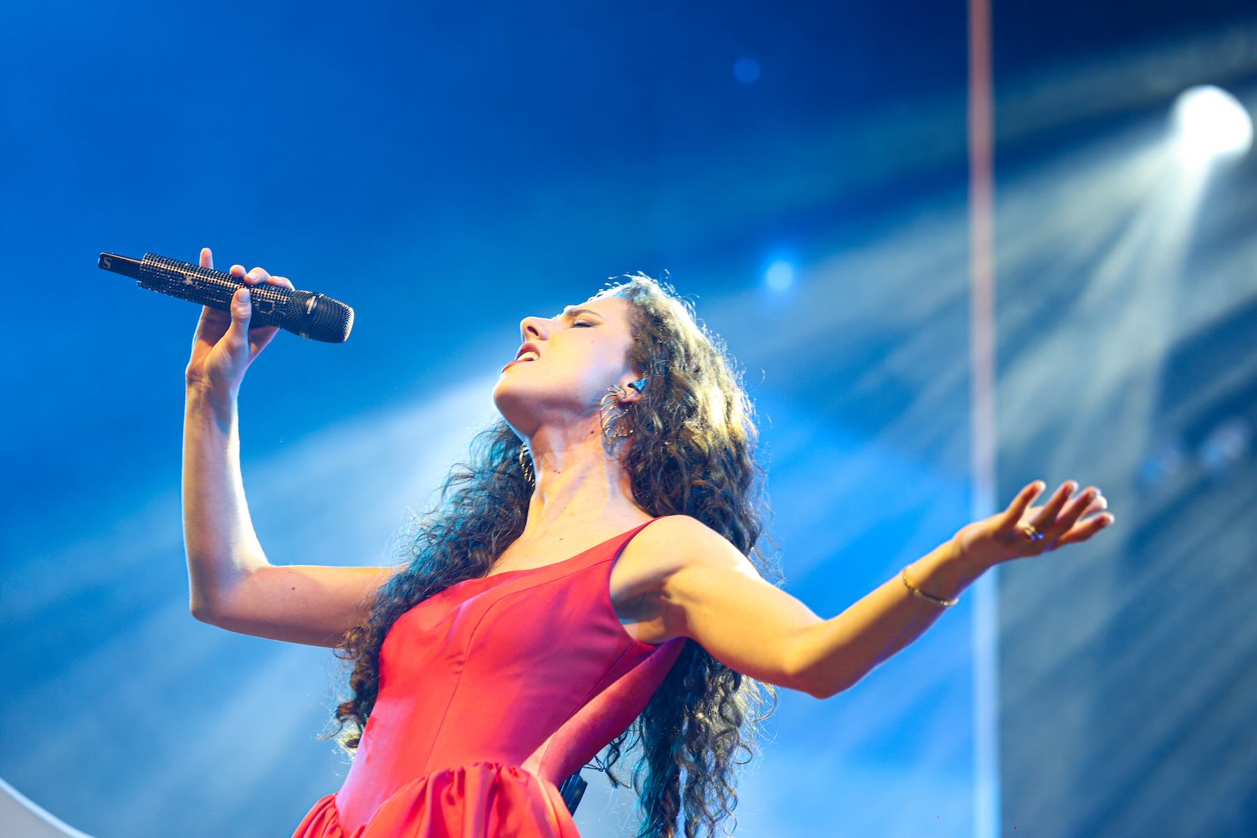 Laura Dalmás em Porto Alegre: clássicos da música italiana no Porto Verão Alegre 1 Laura Dalmás canta em show ao vivo, segurando o microfone no palco iluminado,