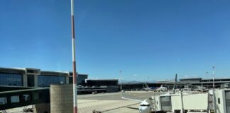 Aeroporto de Milão Malpensa fecha uma pista de março a maio de 2026 - Pátio de estacionamento de aeronaves no Aeroporto de Milão Malpensa com avião comercial conectado ao terminal por ponte de embarque, céu azul ao fundo