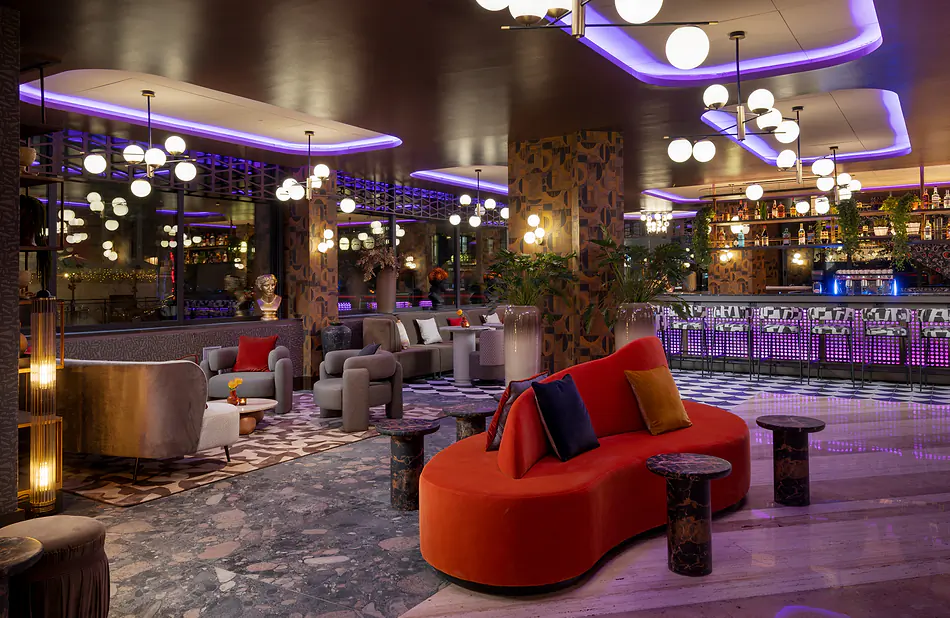 Área de lounge e bar do NYX Hotel Rome em Roma, com sofás coloridos, iluminação moderna e decoração de design