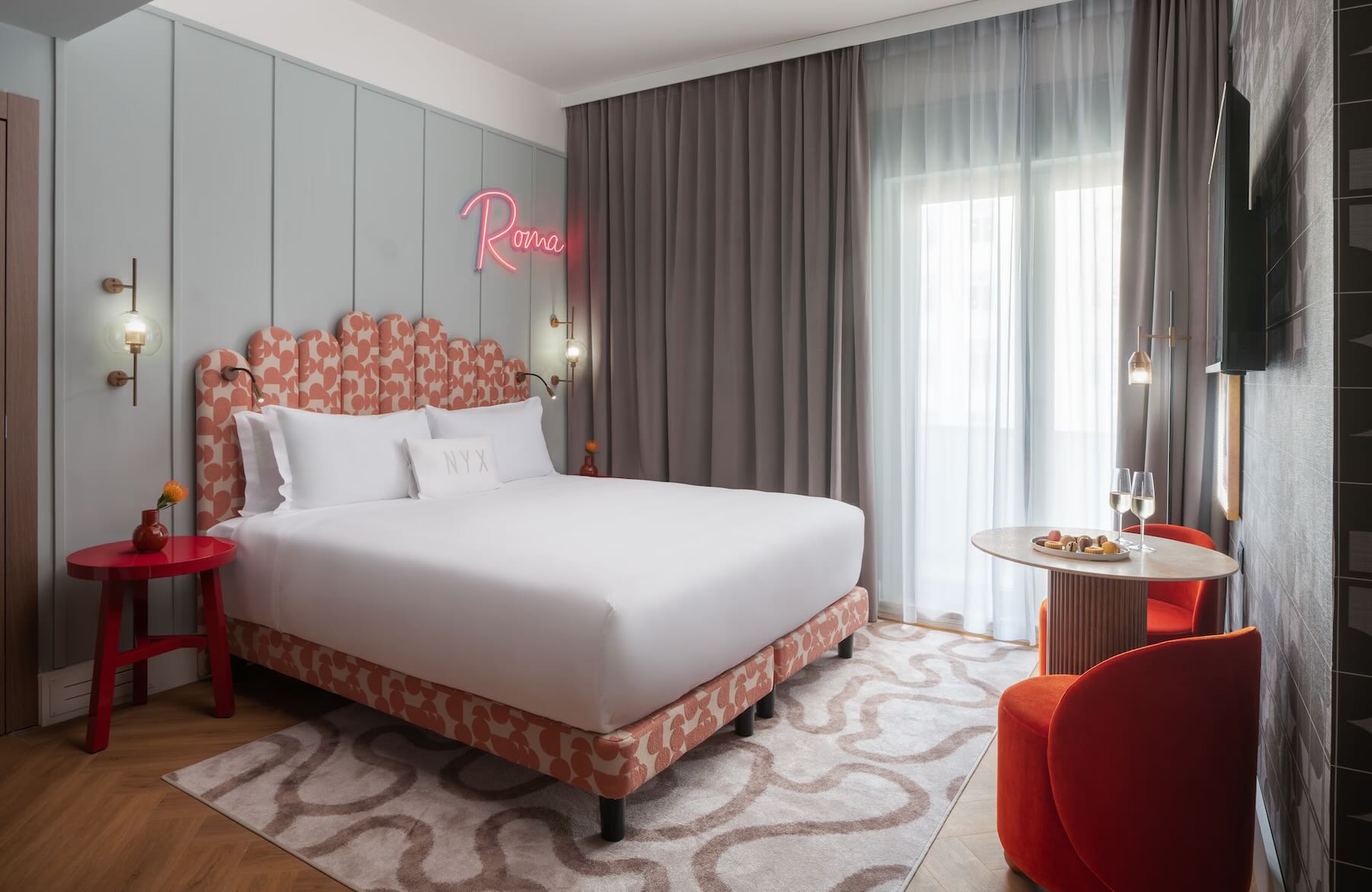 Quarto moderno do NYX Hotel Rome em Roma, com cama de casal, decoração contemporânea e detalhes em tons de vermelho