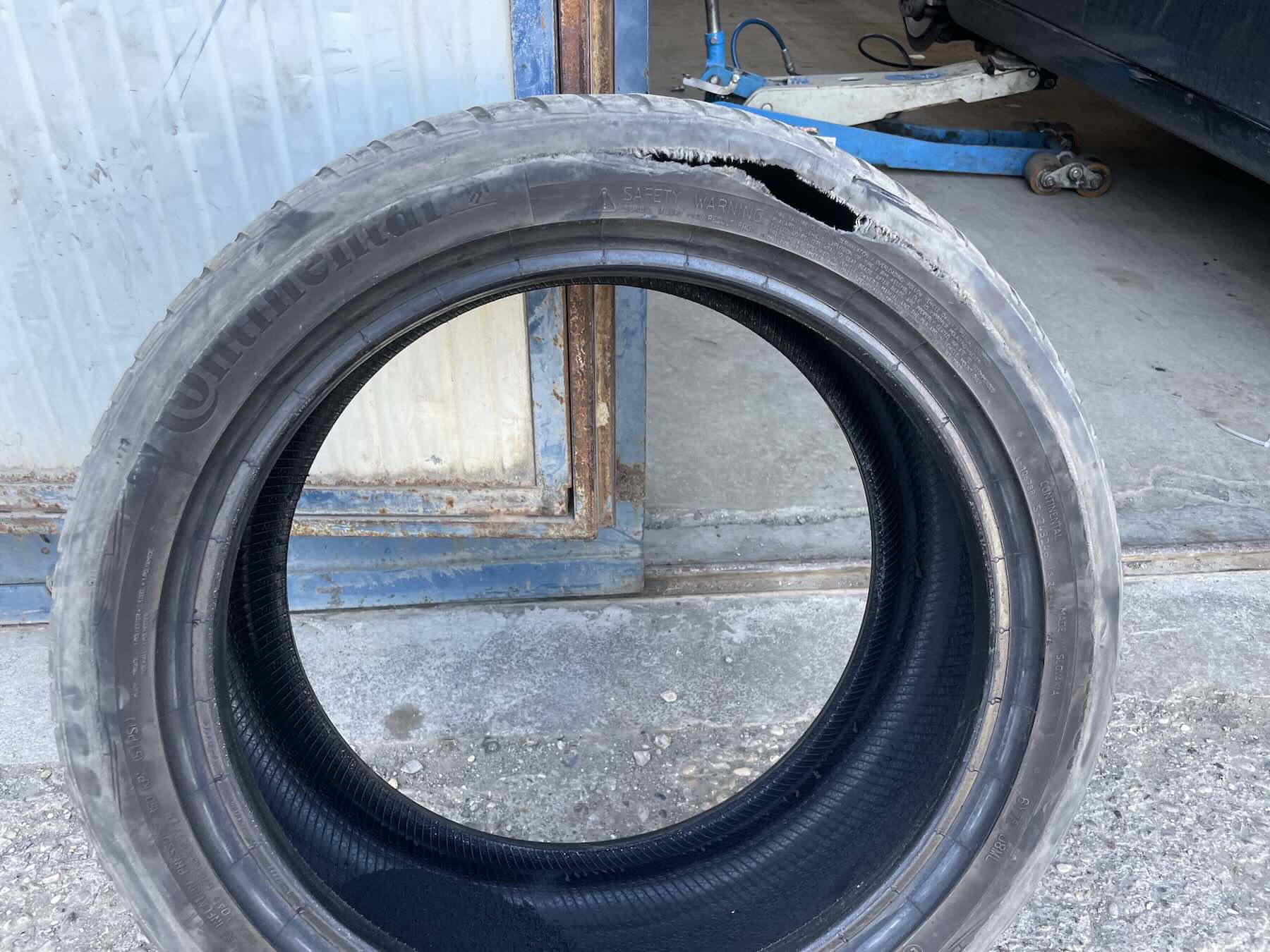 O pneu furado removido pelo borracheiro: por causa do peso do carro e do calor, a parte interna praticamente se rasgou com o contato forçado com a roda.