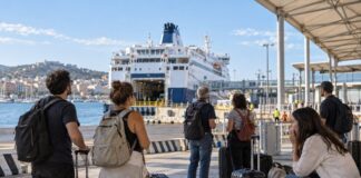 Viajantes com malas esperam o embarque de uma balsa em um porto italiano