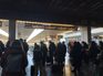 Passageiros aguardam na plataforma de uma estação de trem na Itália, sob o painel de partidas