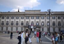 Fachada do Palazzo Reale na Piazza del Duomo, em Milao, com movimento de pedestres e cartazes de exposicoes