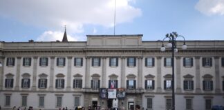 Fachada do Palazzo Reale na Piazza del Duomo, em Milao, com movimento de pedestres e cartazes de exposicoes