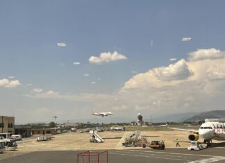 Avião pousando e outro em embarque no pátio de um aeroporto na Itália