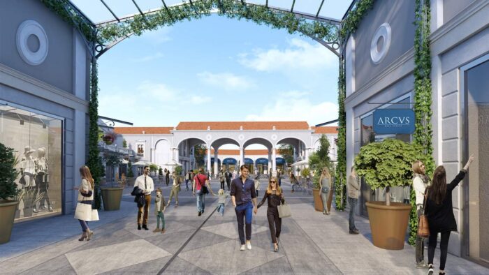 Roma Outlet Village abre em 7 de novembro: descontos, marcas e como chegar saindo de Roma 1 Ilustração do projeto do Roma Outlet Village, com rua de lojas coberta por pérgola, pessoas fazendo compras e arcos brancos ao fundo